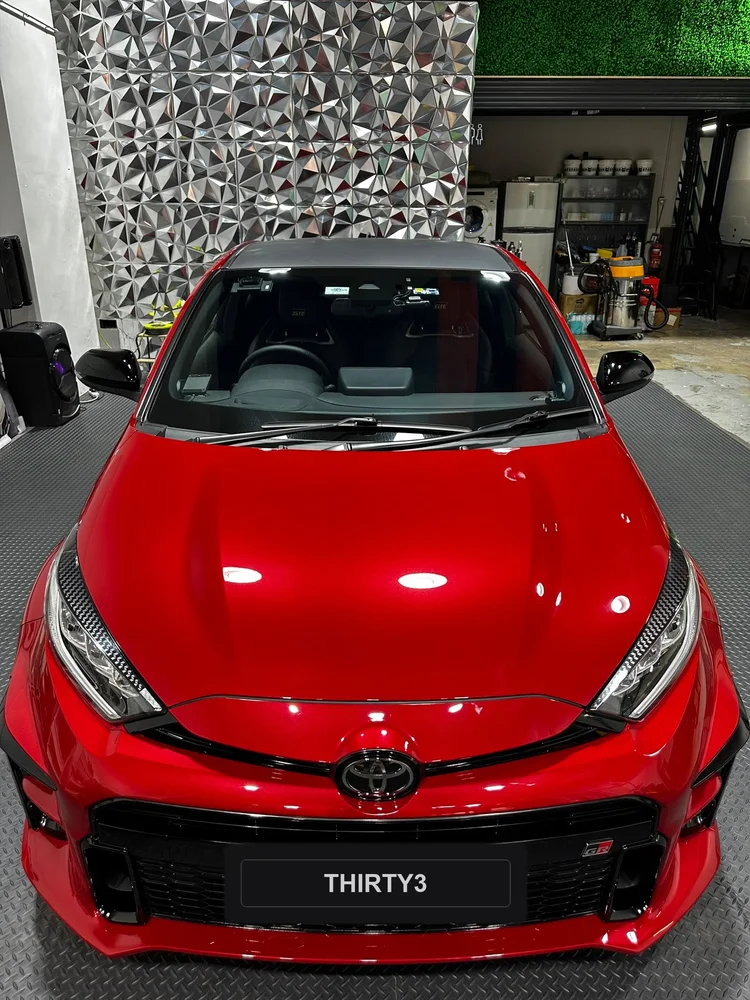Red GR Yaris bonnet seen from the front, reflecting the studio lights