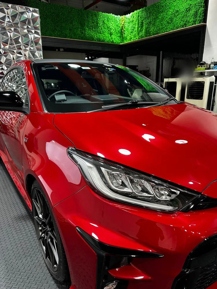 Red GR Yaris in the Thirty3 studio in front of the green wall